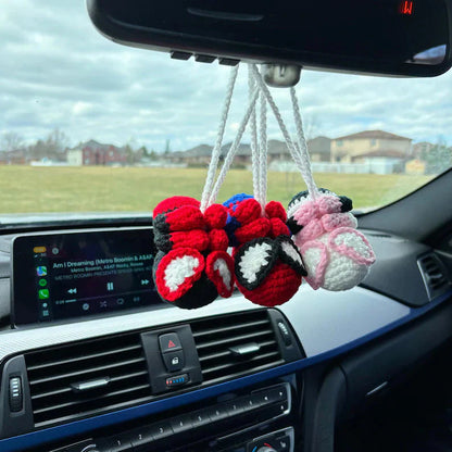 Car dashboard with crocheted bow decorations hanging from the rearview mirror.