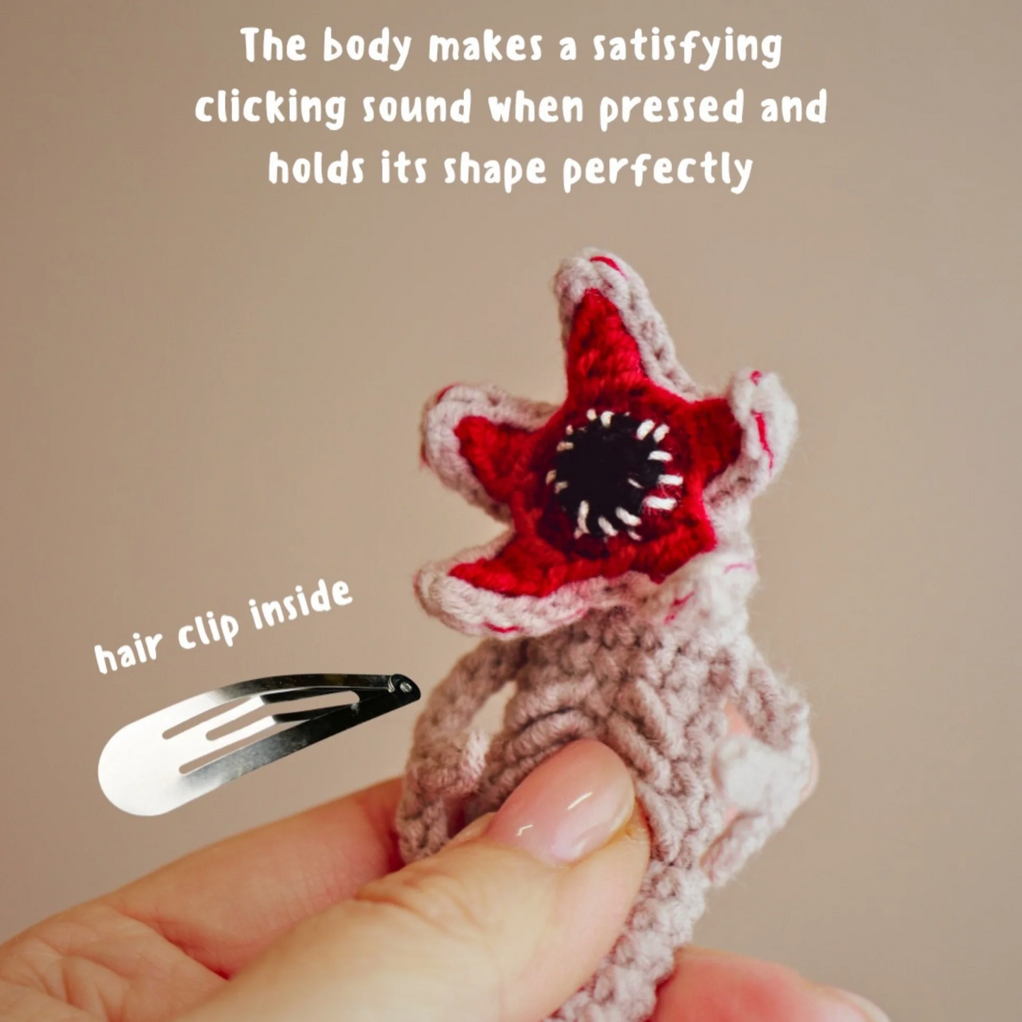 Star-shaped hair clip with red center and white edges, held by a hand against a beige background.